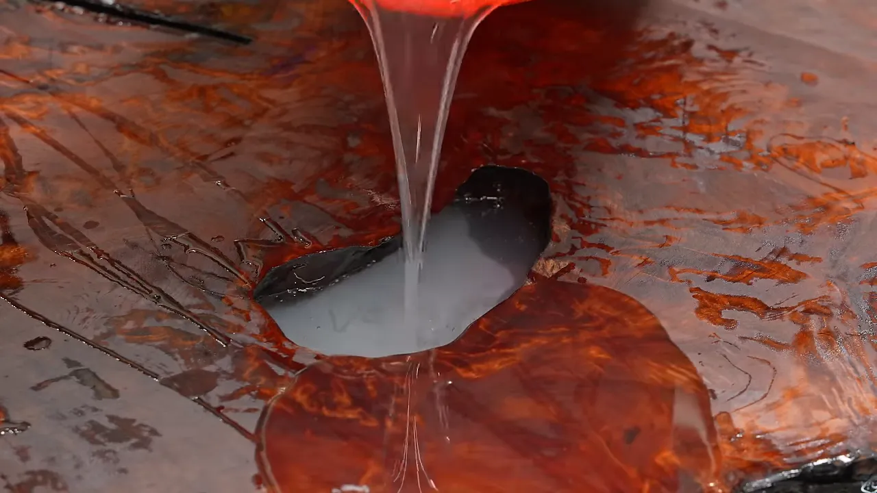 Lightly tinted epoxy pouring into an opening in the redwood slab