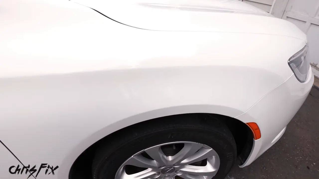 Glossy white front fender after the scratch repair with no prominent dark scratch visible