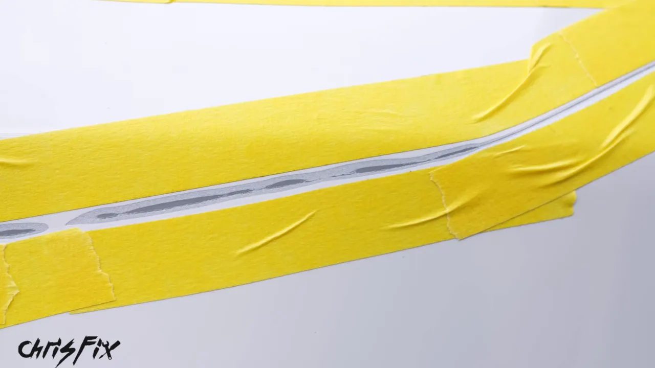 Long scratch in a white fender bordered by yellow masking tape