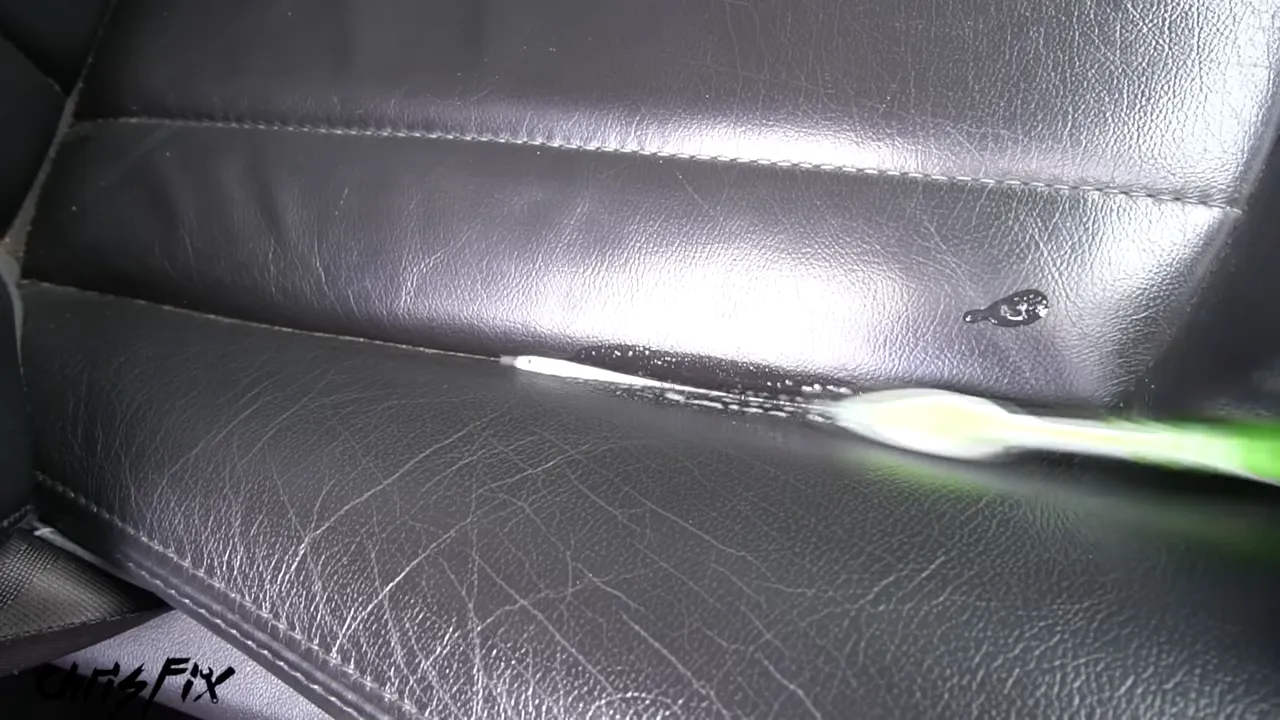 Small brush working cleaner along a seam in a black leather seat