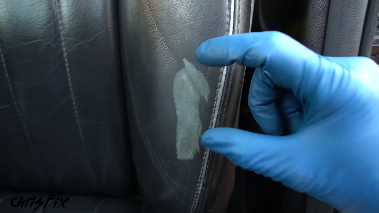 Light-colored worn patch on the outer bolster of a black leather seat