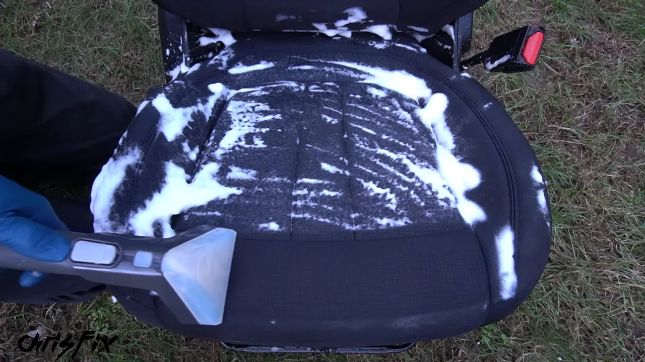Extractor removing foam from a dirty seat and exposing a clean section of dark upholstery