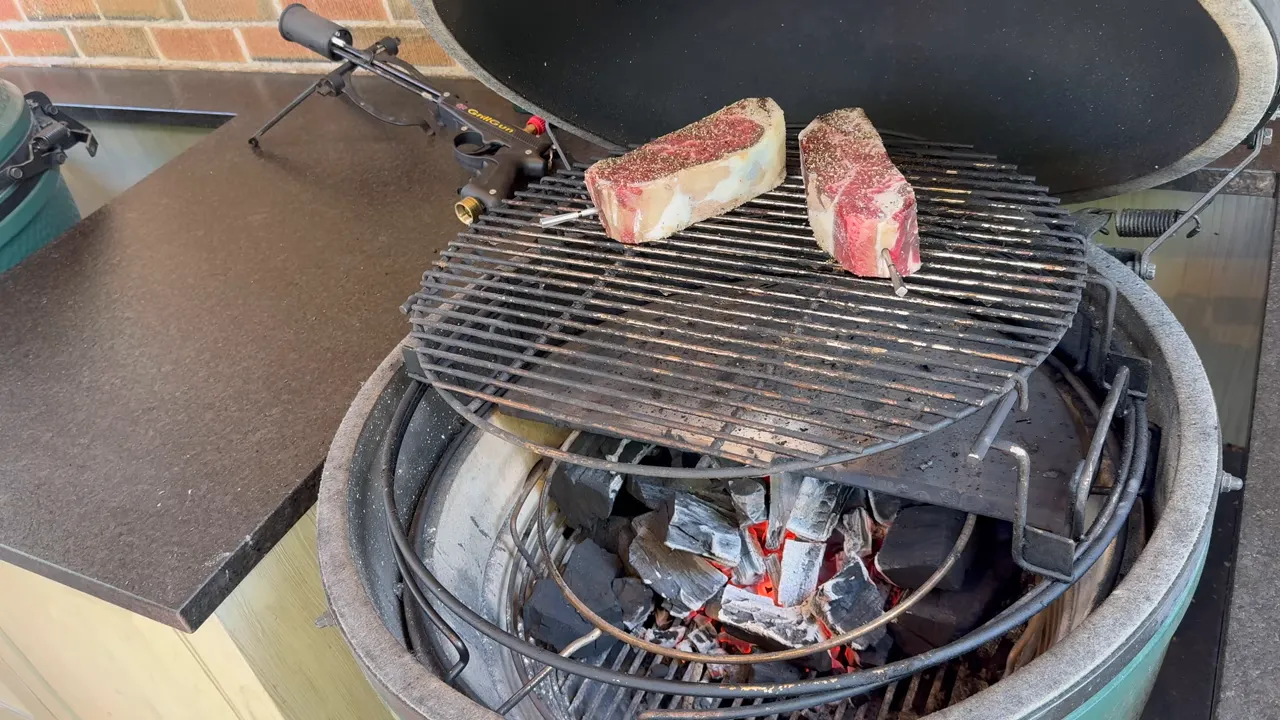 Two steaks with temperature probes on a Big Green Egg grate above a half deflector plate