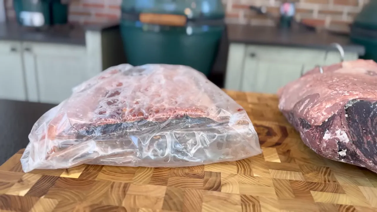 Bagged beef portion on the left and an uncovered aged roast on the right on a wooden board