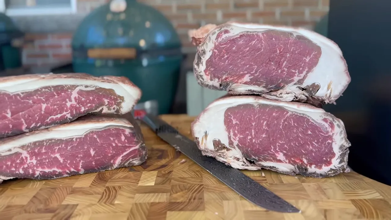 Two flatter raw steaks stacked on the left and two taller raw steaks stacked on the right