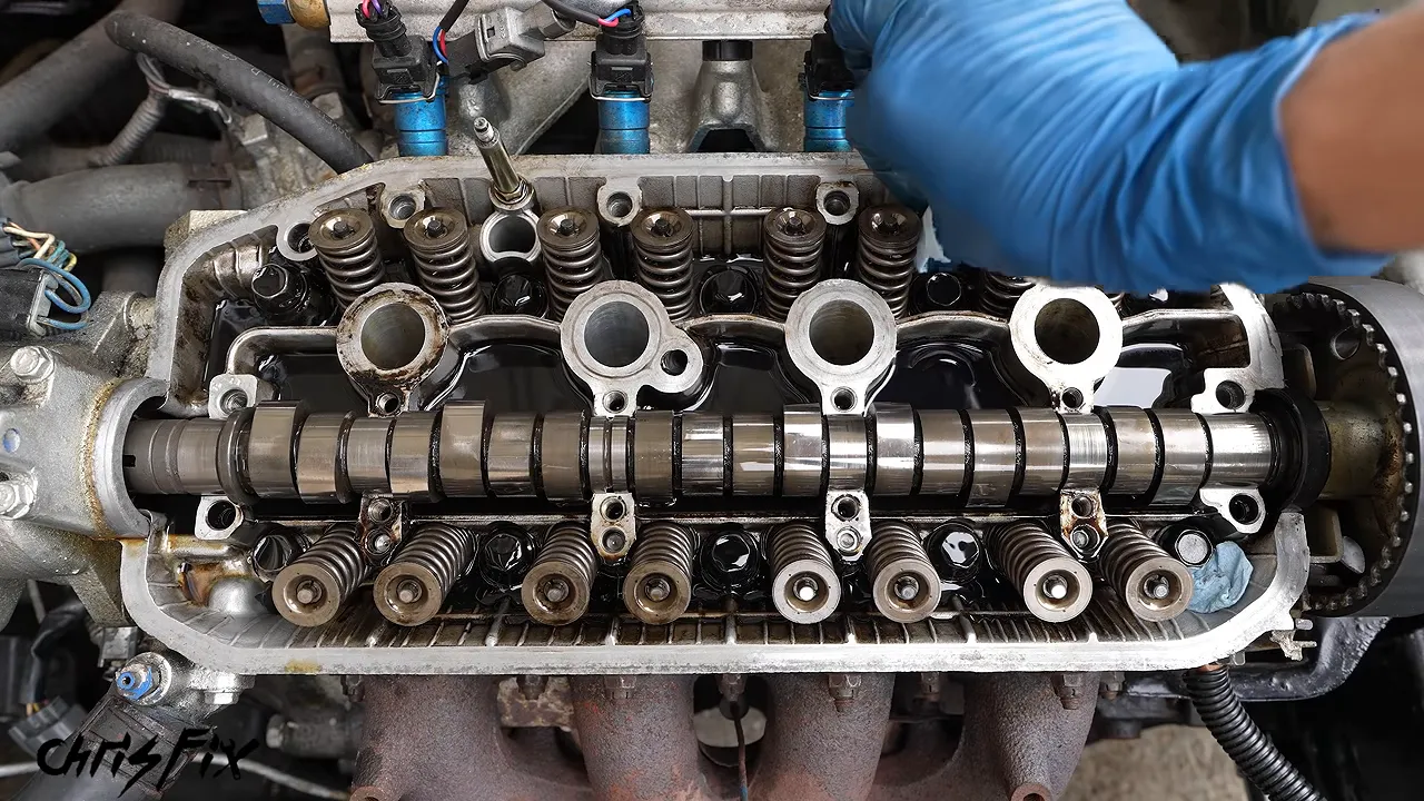 Exposed cylinder head with white towel pieces placed in openings around the valve springs and camshaft
