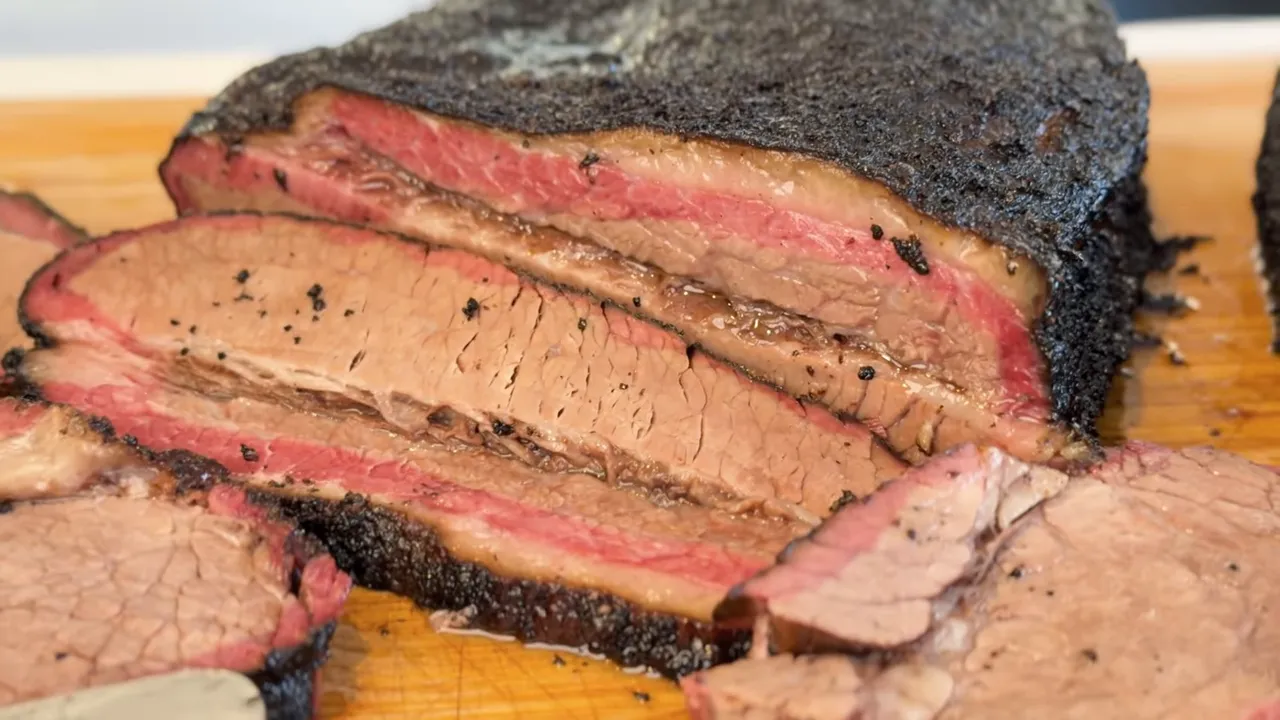 Sliced brisket on a wooden board showing dark bark, a pink smoke ring, and a seam of fat