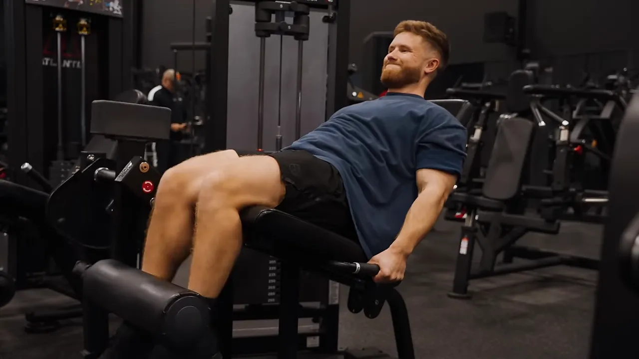 Lifter performing a leg extension with torso reclined against an angled backrest