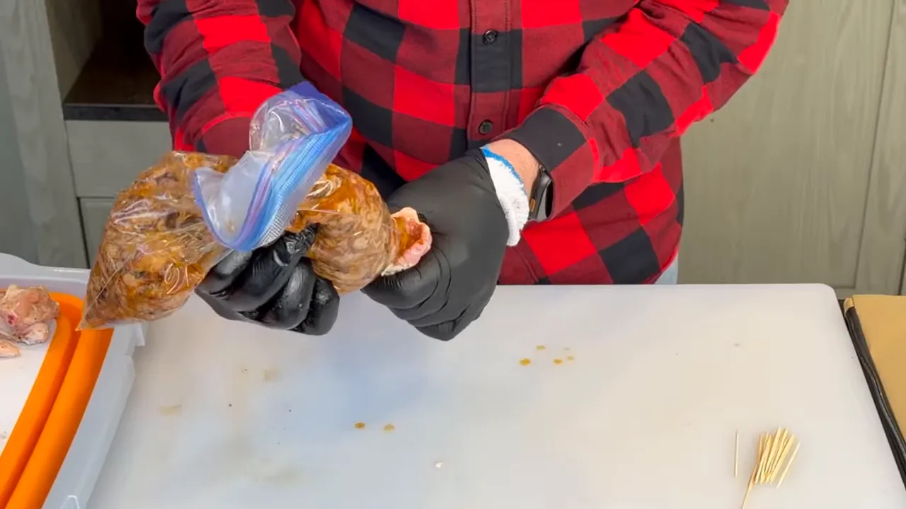 Pulled pork being squeezed from a zip-top bag into a deboned chicken wing