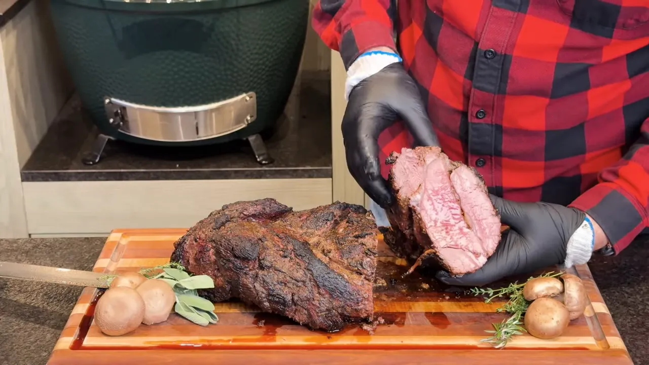 Gloved hands holding a sliced braided tenderloin cross-section with pink centers and more cooked edges