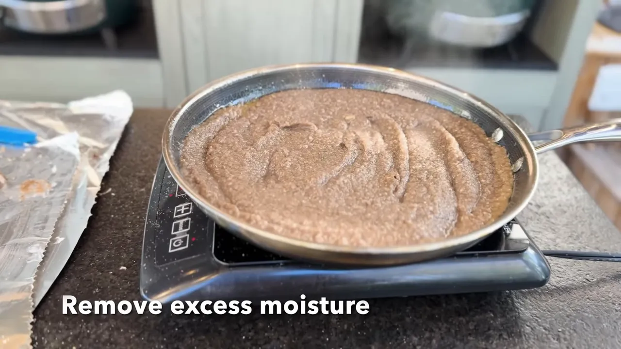 Thick mushroom paste in a skillet with on-screen text reading Remove excess moisture