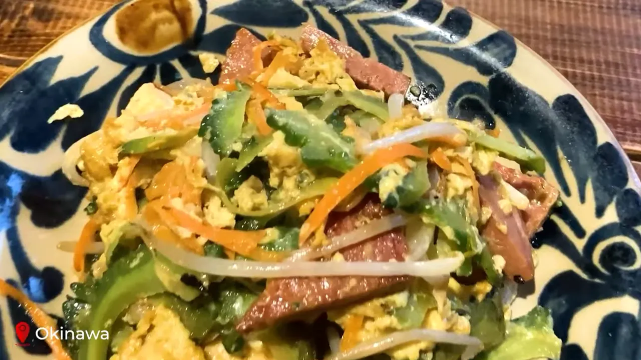 Close-up of goya champuru (Okinawan bitter-melon stir-fry) with egg, sliced pork and bean sprouts in a patterned bowl