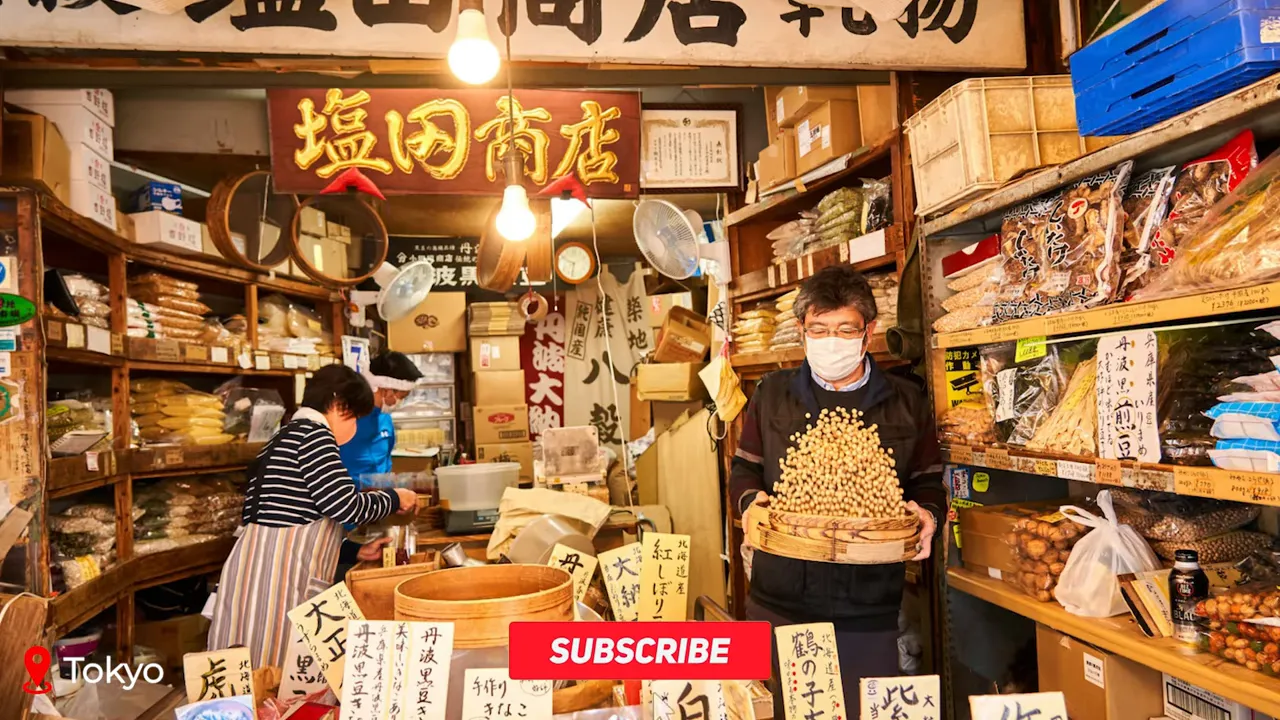 Toyosu Market stall with vendor holding a basket of soybeans surrounded by packaged goods and handwritten signs