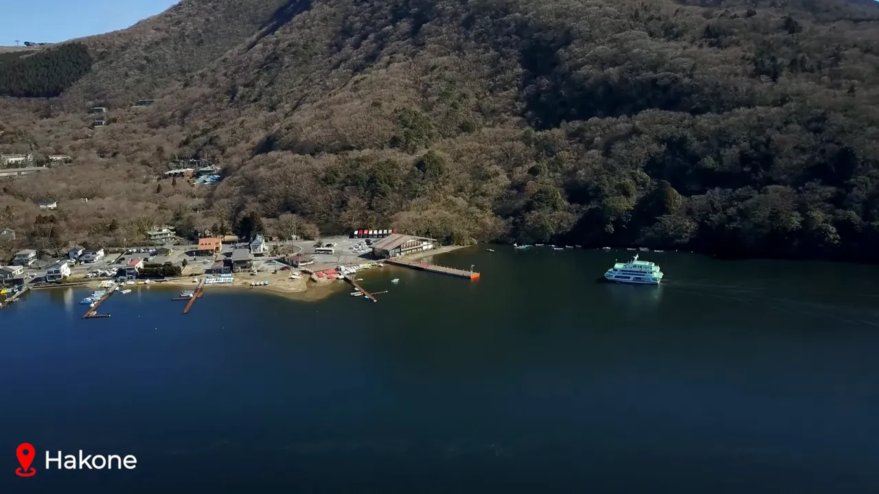 Aerial view of Lake Ashi in Hakone showing shoreline, docks and a sightseeing ferry on calm water