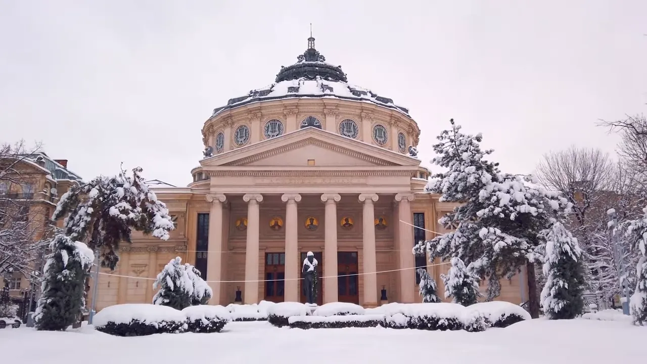 Snow-covered neoclassical domed building with columned portico and snow-laden trees in front