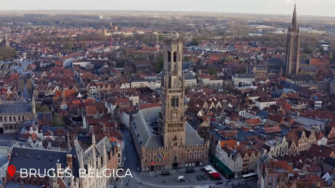 Wide aerial panorama of Bruges showing the Belfry rising above stepped‑gabled houses around the main square.
