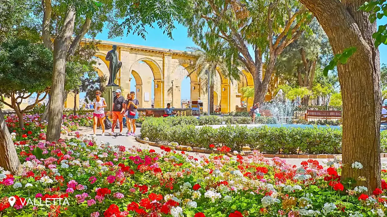 Upper Barrakka Gardens with colorful flowerbeds, fountain and arched promenade overlooking the Grand Harbour in Valletta