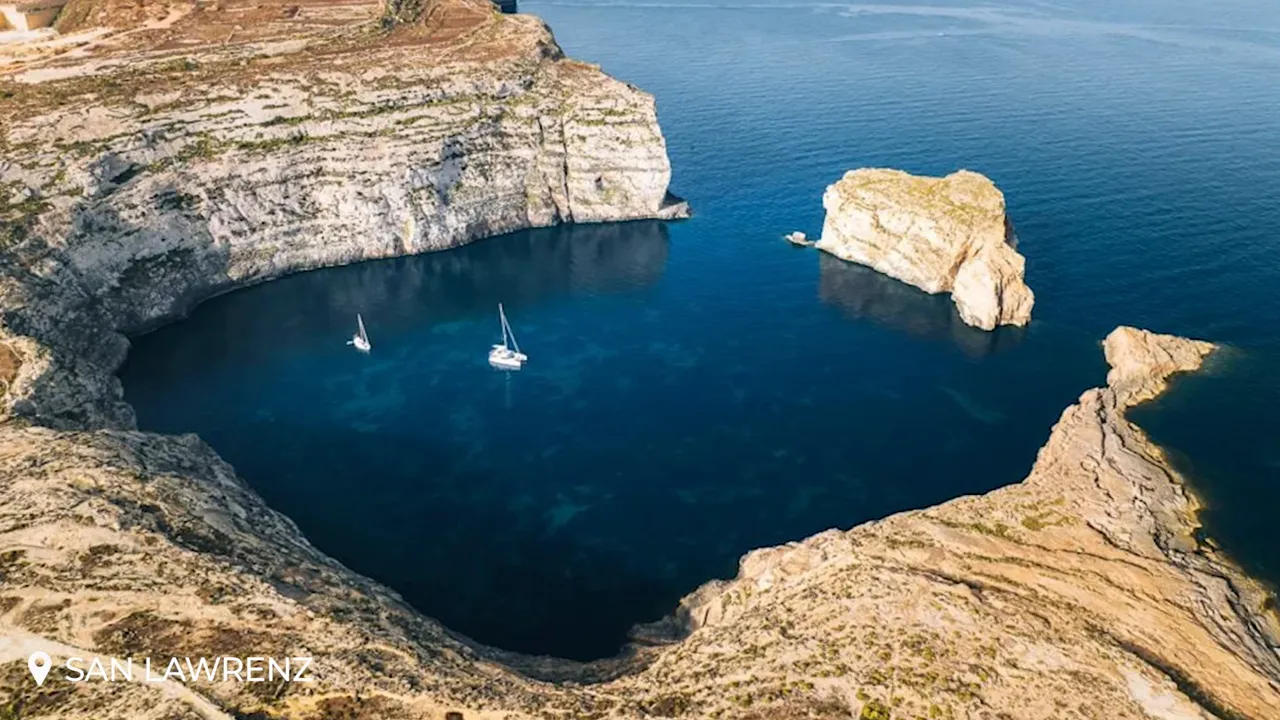 Aerial view of Dwejra's circular inlet (Blue Hole / Inland Sea) with anchored sailboats in deep blue water at San Lawrenz