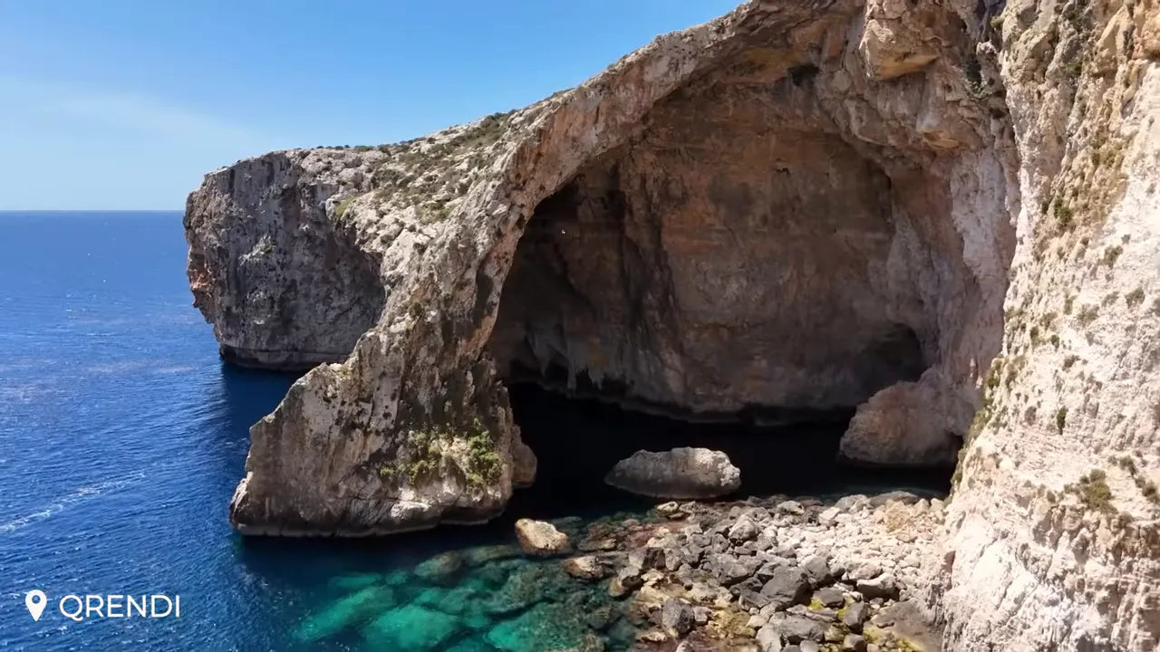 Sunlit view of the Blue Grotto at Qrendi showing a limestone arch, cave interior and clear turquoise water