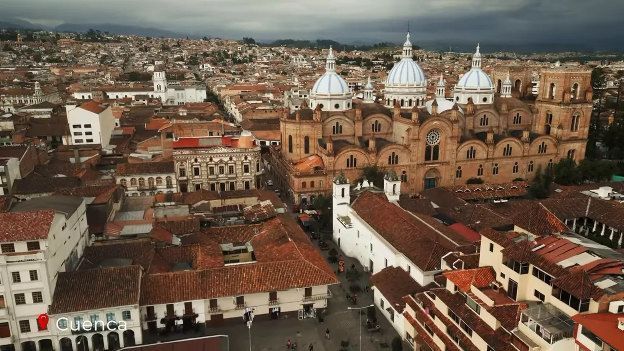 Aerial shot of Cuenca cathedral with prominent blue domes and the colonial plaza below