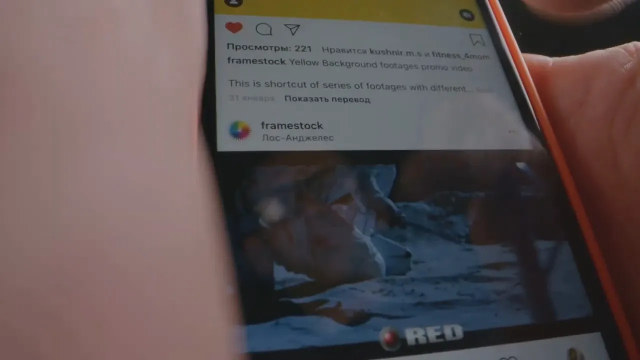 close-up of a smartphone screen showing an Instagram post being scrolled with account name and media visible