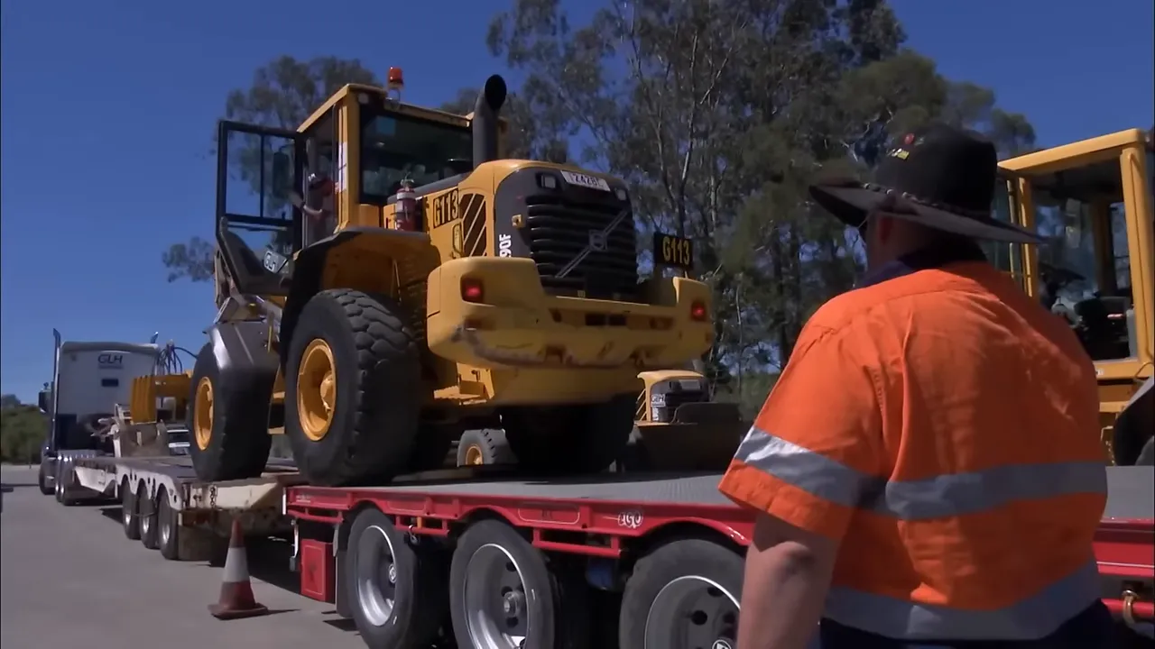 Loader being driven onto the hired drop deck without ramps