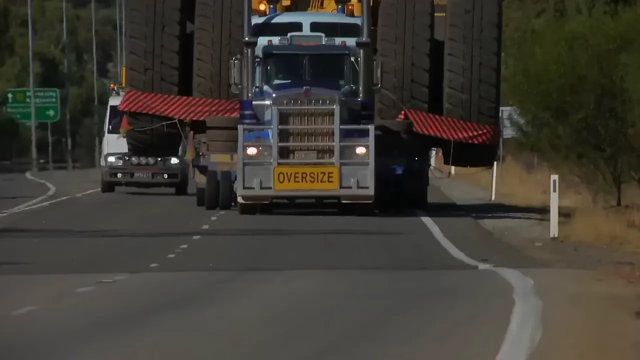 Another truck helps pull the oversize load up a melting hill