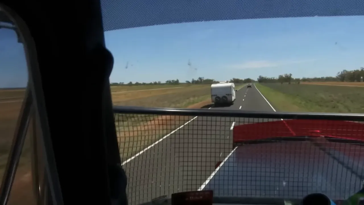 Long outback road with a caravan ahead slowing traffic
