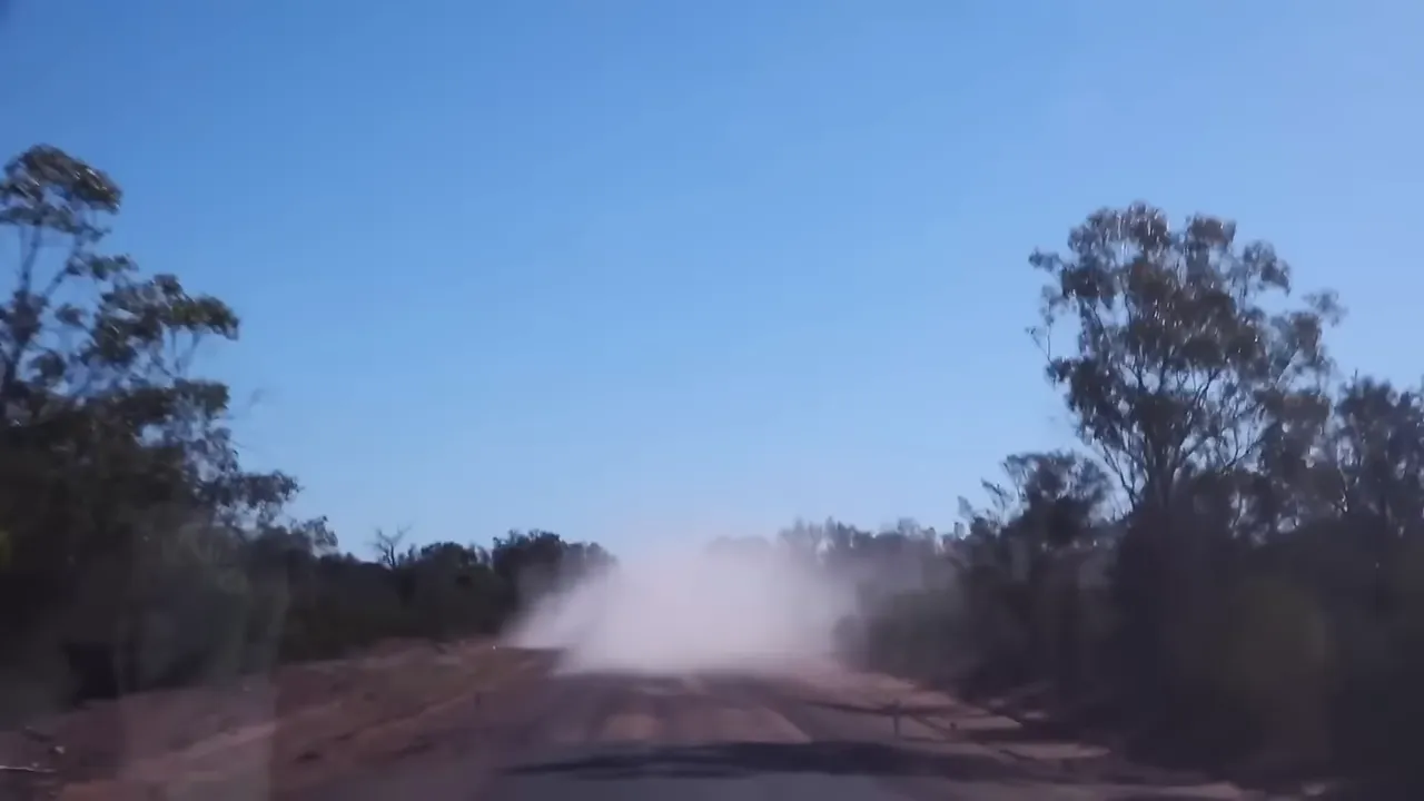 Convoy kicking up a wall of dust as trucks pass