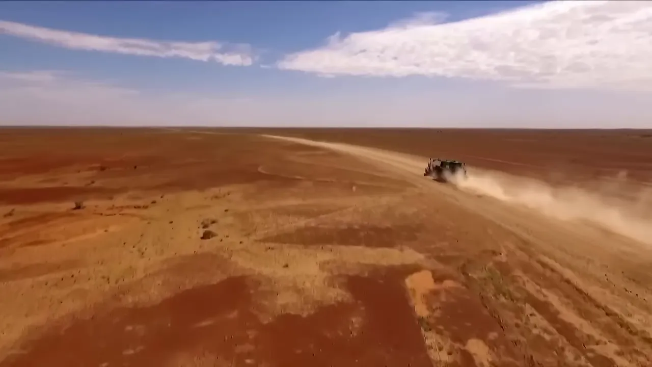 Wide shot of the Birdsville Track, long red dirt road stretching into the horizon