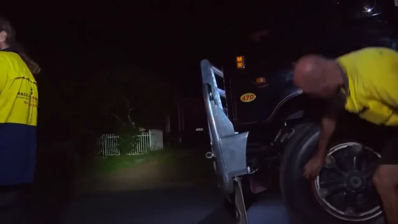 Crew replacing a flat tyre beside the road at night