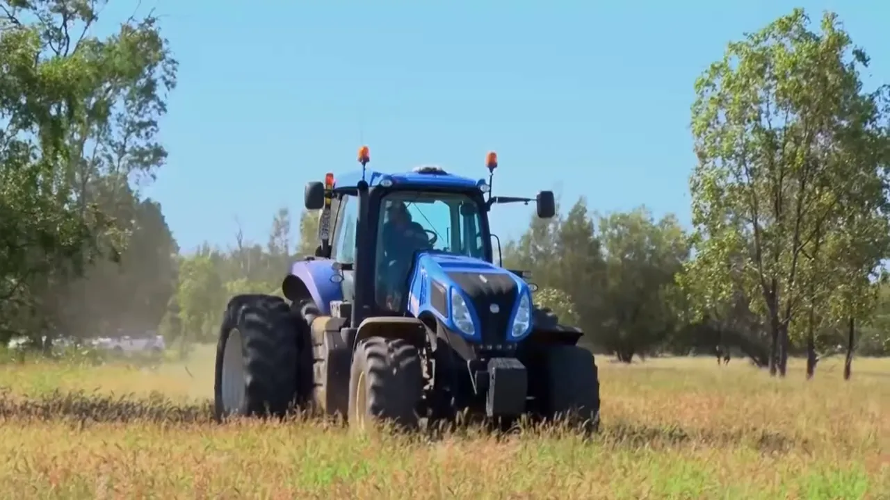Tractor towing the bogged truck through wet paddock to rescue the convoy