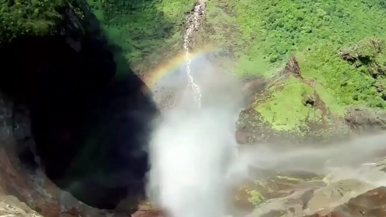 Cascada con niebla y arcoris delante de una cavidad oscura en la roca evocando un espacio oculto