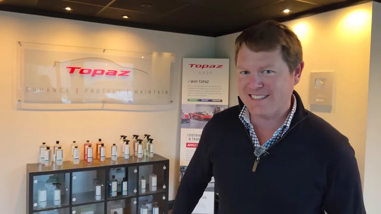 Interno del centro Topaz con bottiglie di prodotti per detailing e tecnico davanti alla parete brandizzata