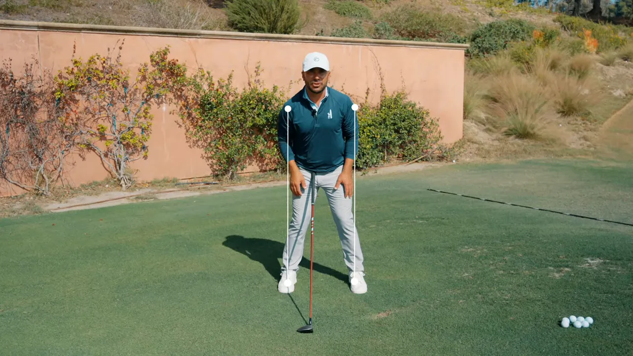 Golfer at the 3-wood address demonstrating a wide stance and forward ball position with alignment markers.