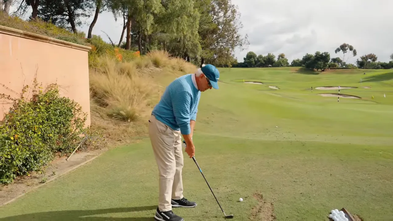 Golfer at address on a practice fairway preparing to take a shot, demonstrating forward tilt and ball position.