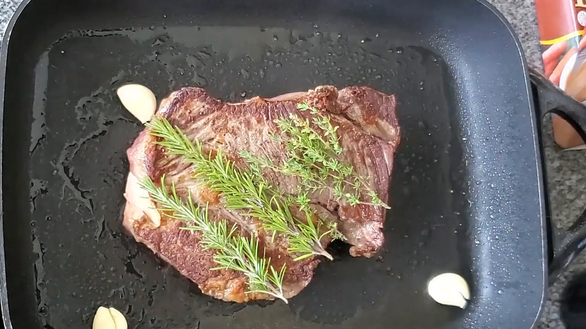 Adding garlic and herbs on top of the seared roast.