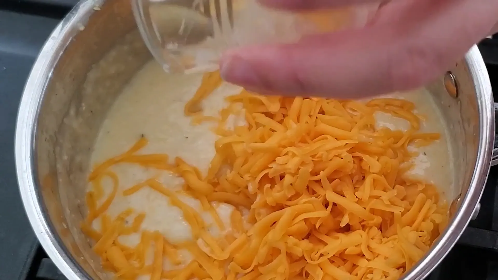 Mixing shredded cheese into the grits.