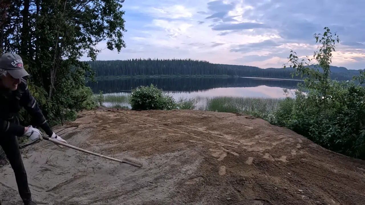 Off grid life - leveled fire pit area overlooking the lake with a bench and chairs nearby