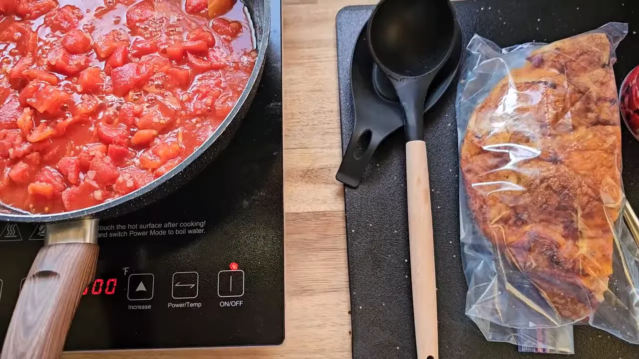 Off grid life - pan of pasta mixed with tomatoes cooking on an induction burner