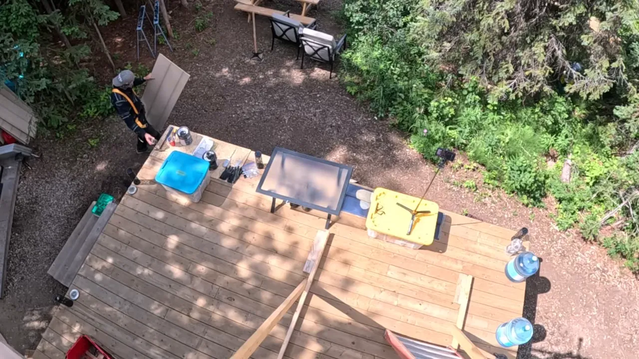 Off grid life - overhead view of work area with boards, tools, and ladder beside the cabin deck