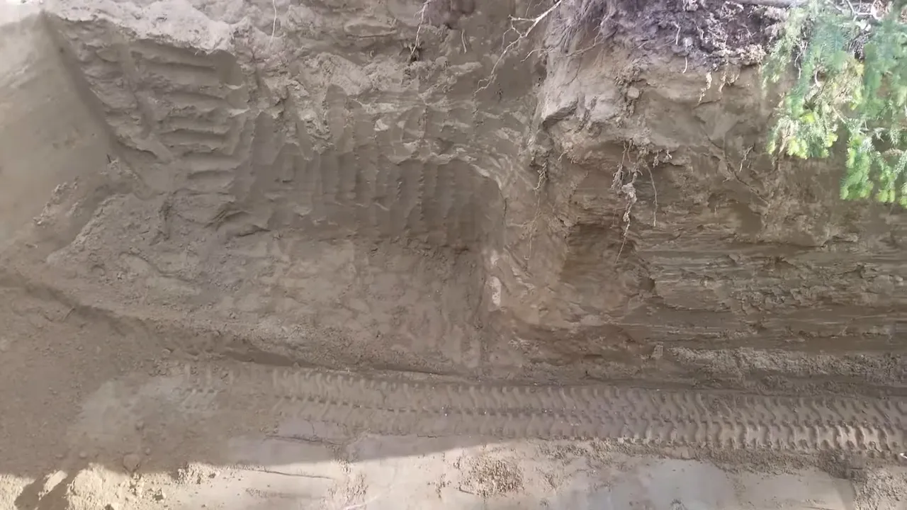 Off grid life - wide overhead view of deep excavation with spoil pile and steep interior walls
