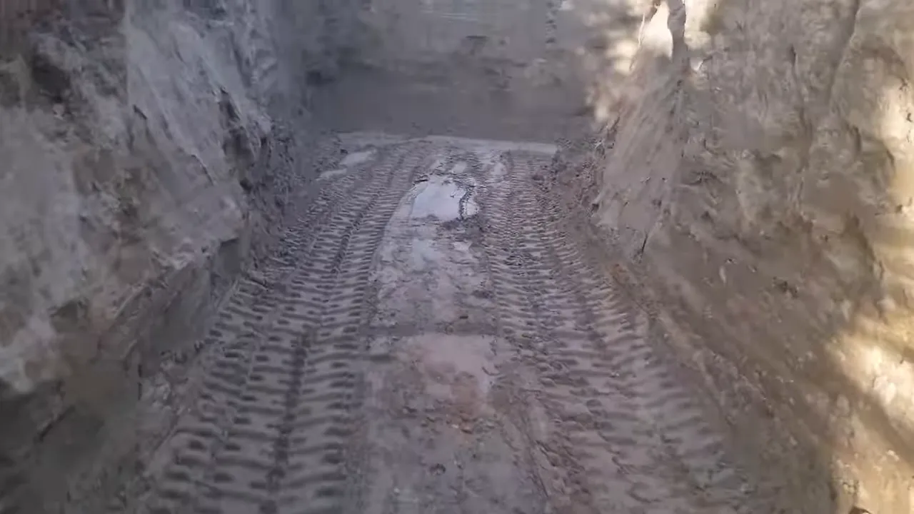 Off grid life - view looking through the finished excavation floor and sloped walls with tracked marks visible