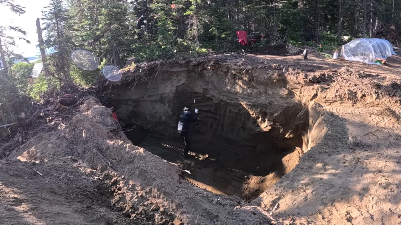 Off grid life - broad view of excavation walls being shaped into gentler slopes around the pit