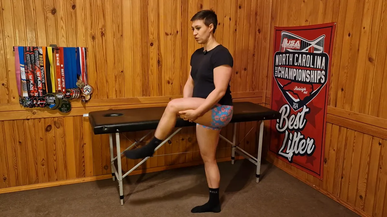 Instructor holding the lifted knee while performing 'stir the soup' balance and coordination drill