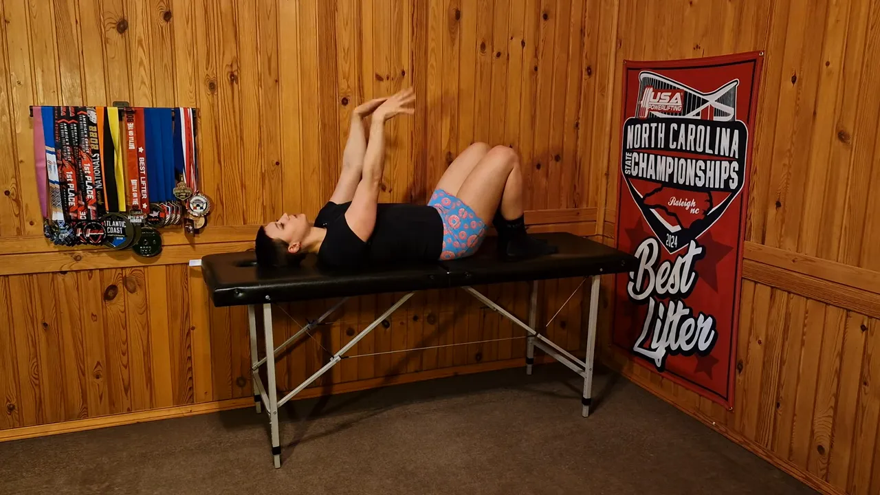 Person on a table demonstrating a 'stir the pot' arm warmup with hands and wrists moving together