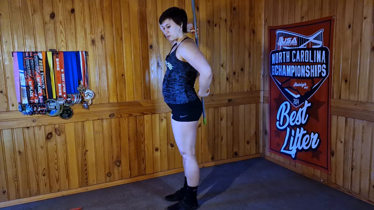 Side profile of coach with a dowel placed along her back, demonstrating a neutral spine and hip position.