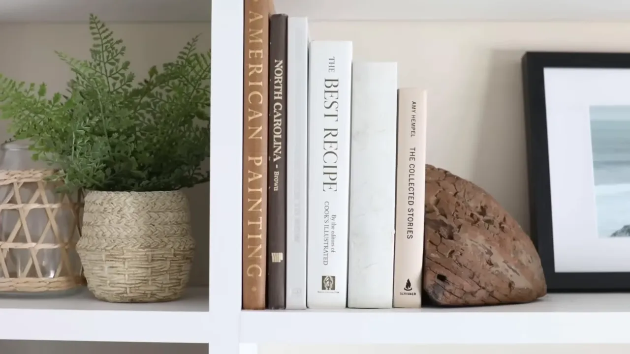 White books and a decorative stone arranged on a shelf beside a woven plant basket