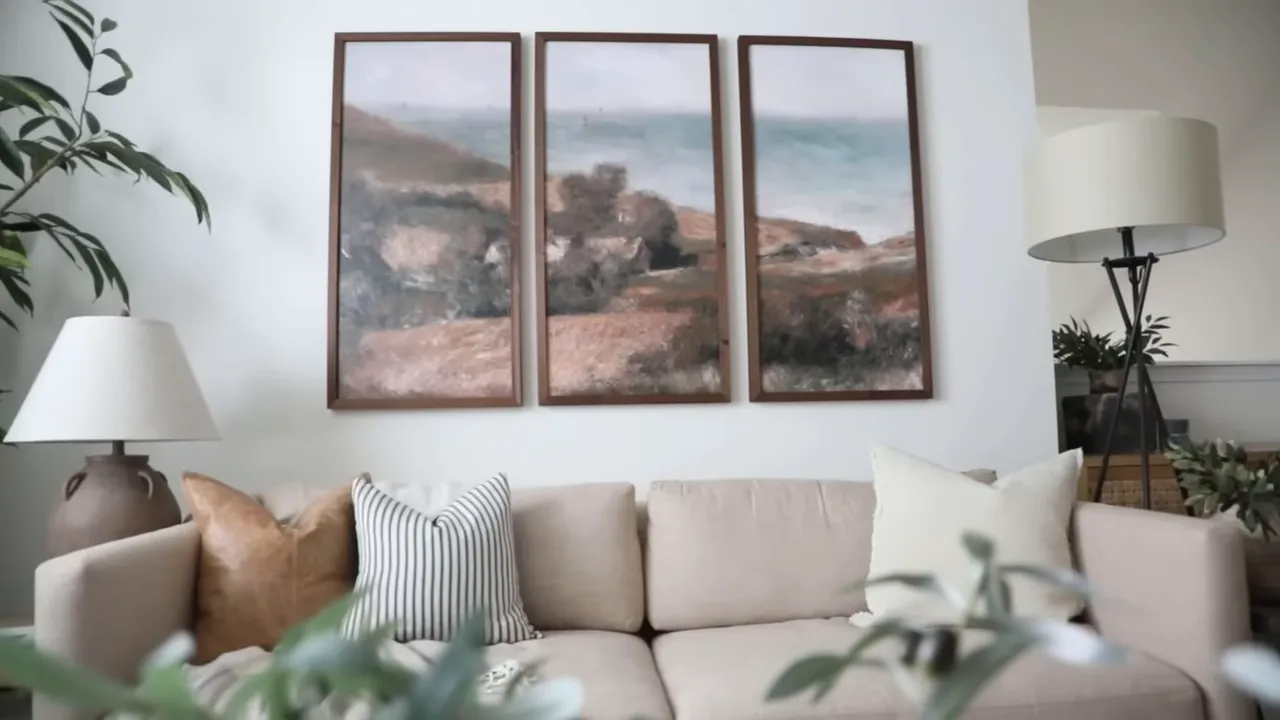 Three framed landscape artworks above a neutral sofa
