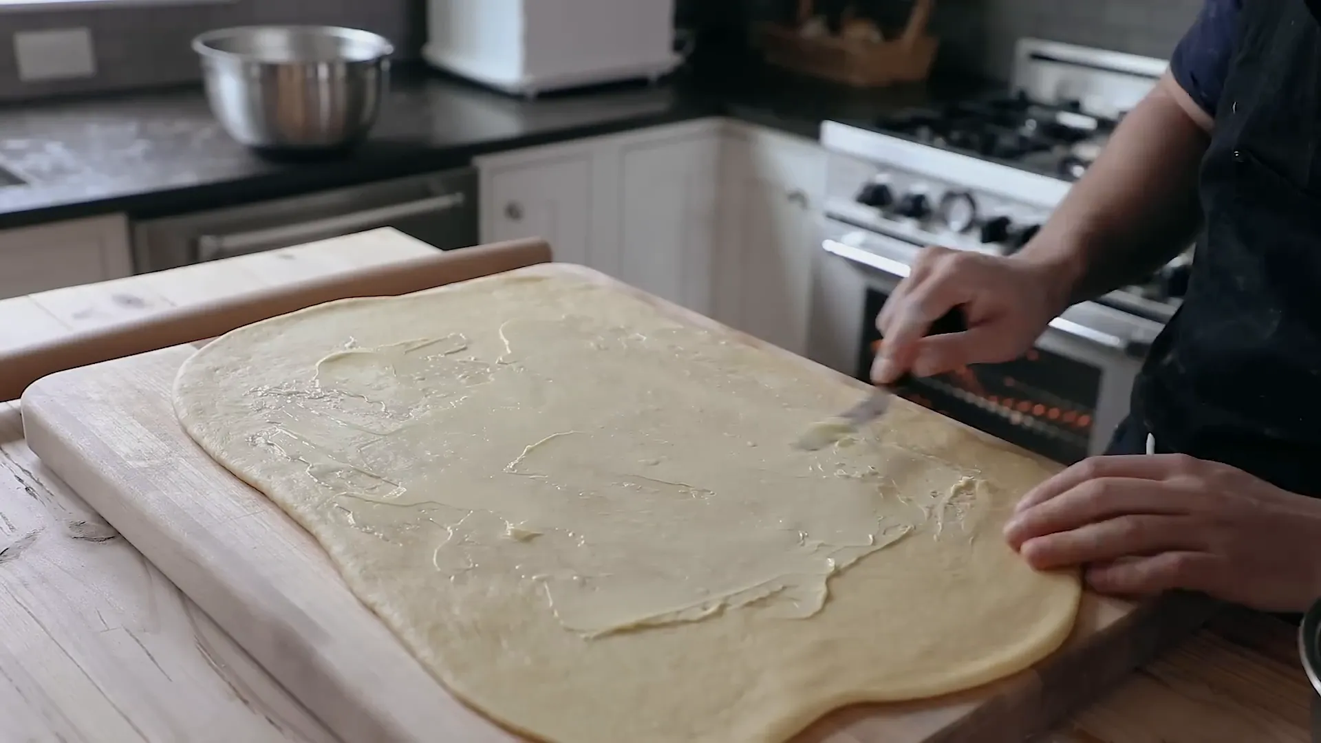 Spreading butter and cinnamon sugar on the dough.